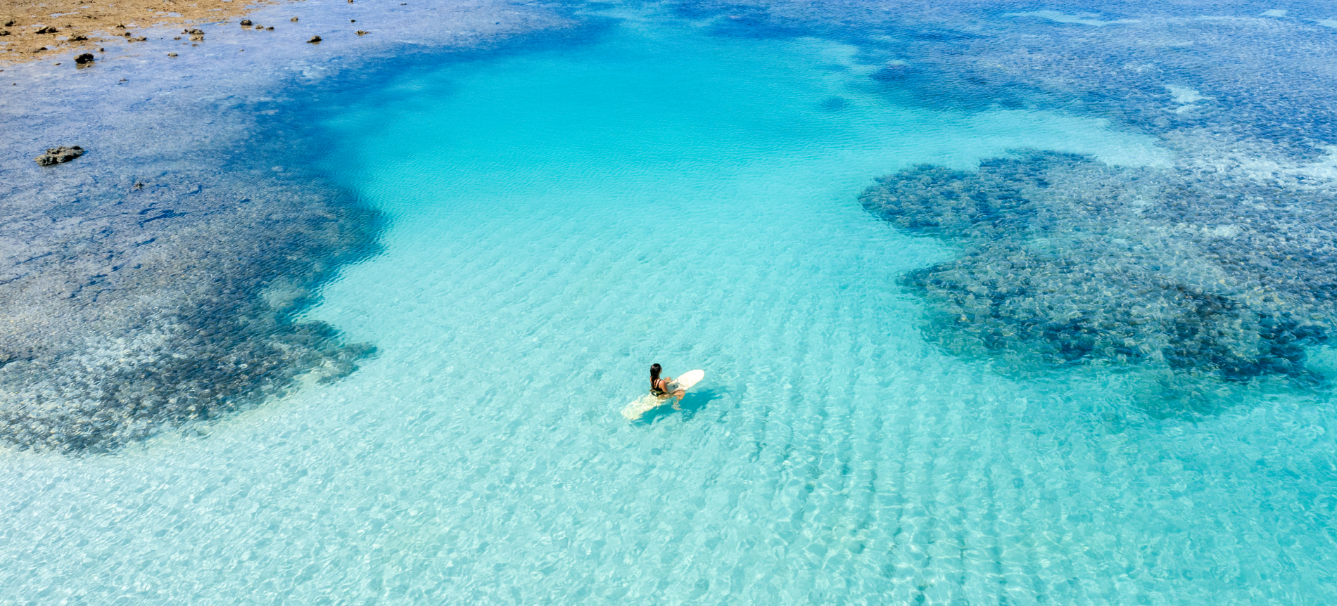 Mulher sentada em prancha nas piscinas naturais de Japaratinga.