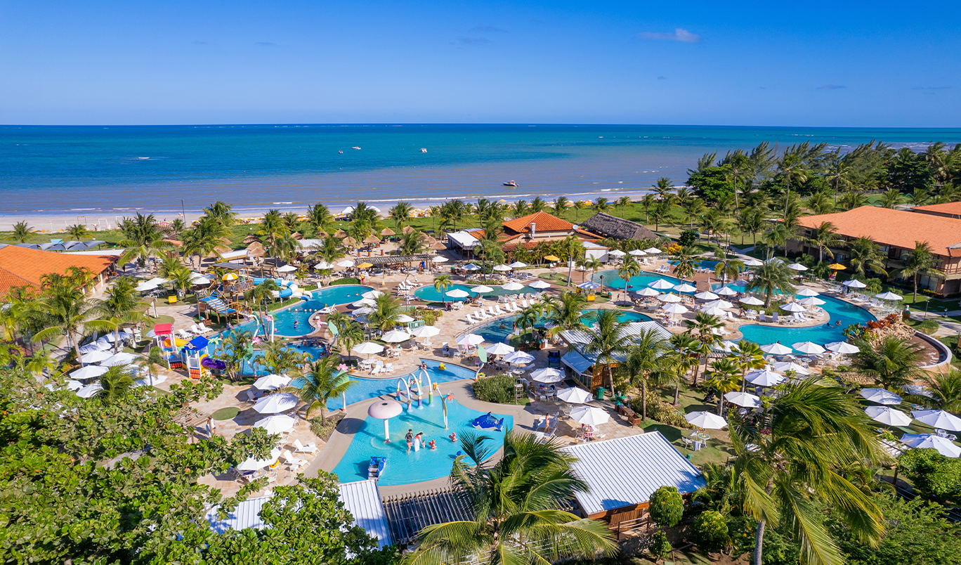 Vista aérea do Salinas Maragogi com vista pra o mar, um rio cruzando pelo meio do resort e áreas de lazer.