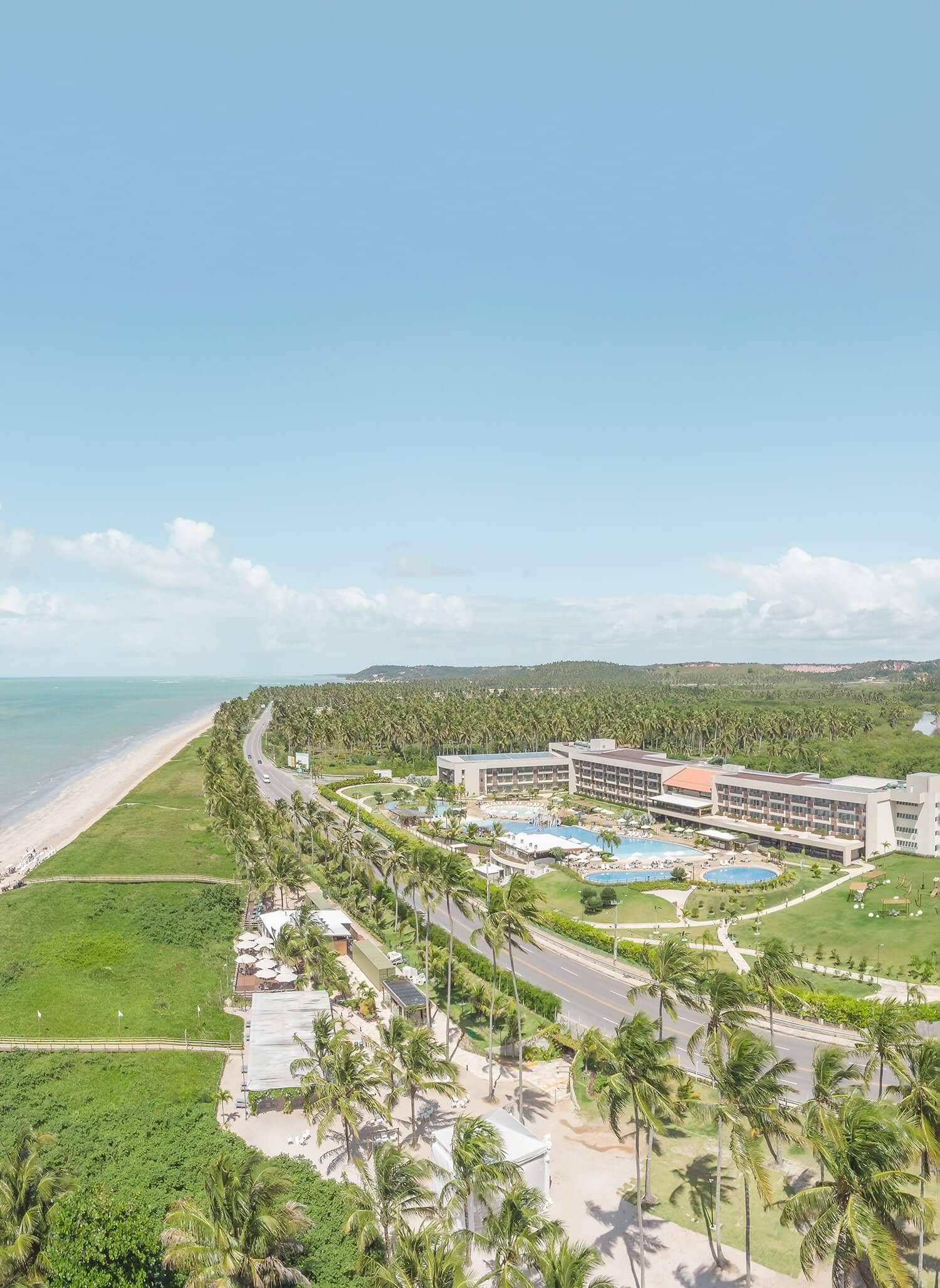Parte da estrutura do Japaratinga Lounge Resort e da praia de Japaratinga, em Alagoas. É possível ver parte do complexo de piscinas, alguns de seus prédios e restaurantes. Além disso, há uma vasta vegetação ao redor.
