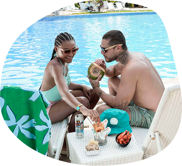 Casal brindando com drinks ao lado da piscina.