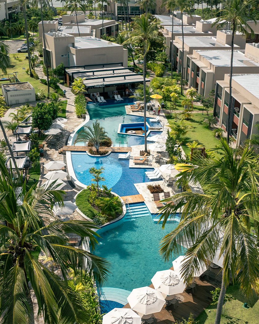 gardens mango bar Vista aérea da área de lazer das Gardens, com piscina, guarda-sois e espreguiçadeiras. Ao fundo o Mango Bar, e tudo com bastante vegetação ao redor.